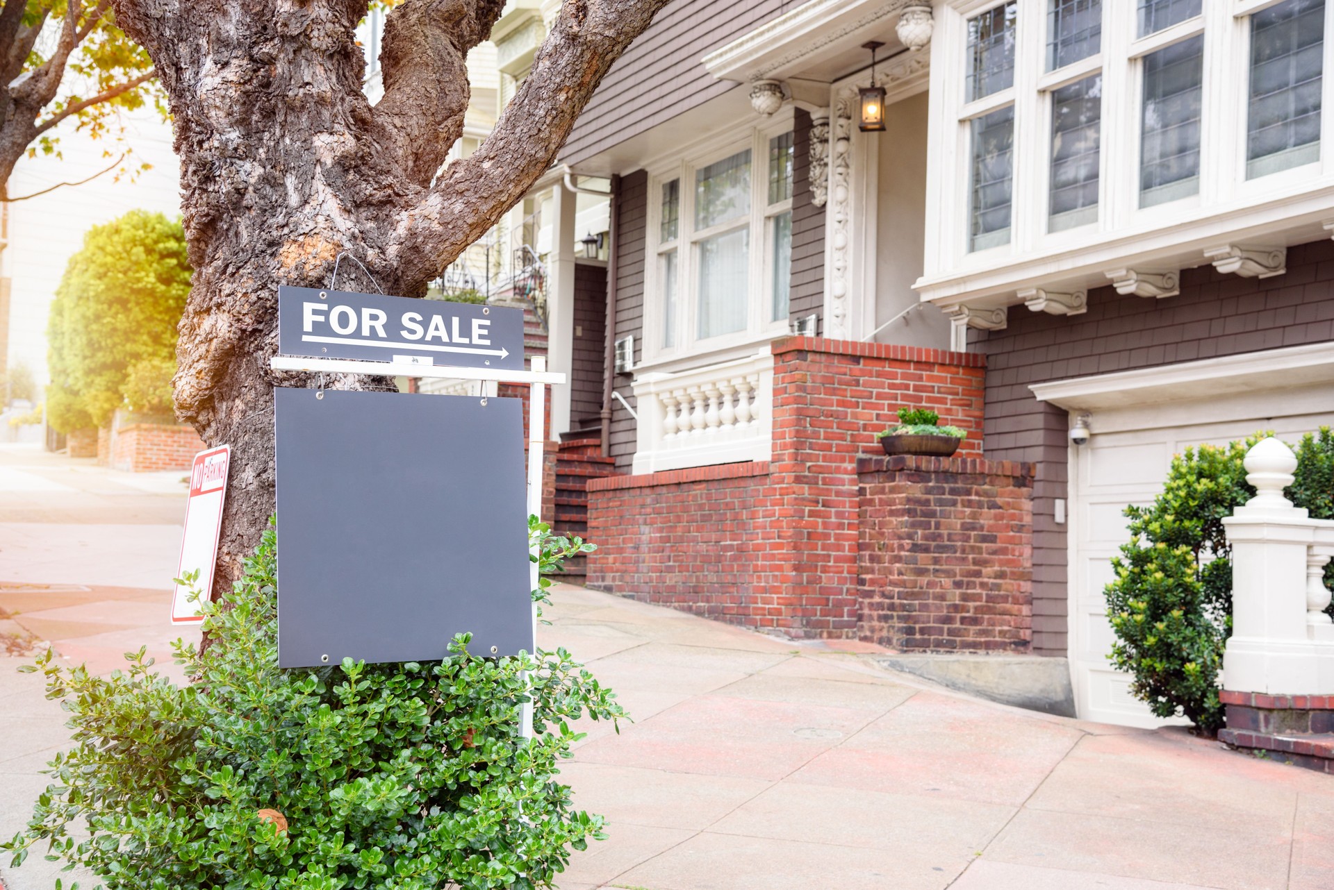 Real estate sign on the sidewalk in front of a house on sale
